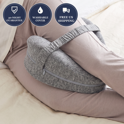 Gray side-sleeper knee pillow strapped between the knees in bed, with 30-night guarantee, washable cover and free US shipping badges