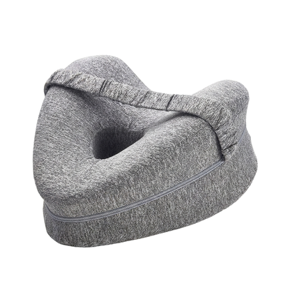 Grey heart-shaped memory foam knee pillow with hollow center, elastic leg strap and zipper on a white studio background